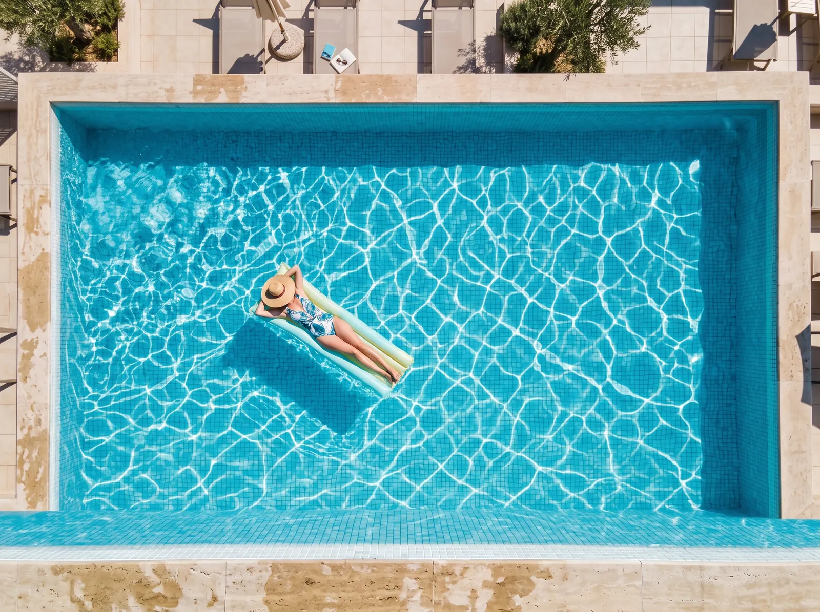Piscina vista de cima com água cristalina e uma pessoa numa boia